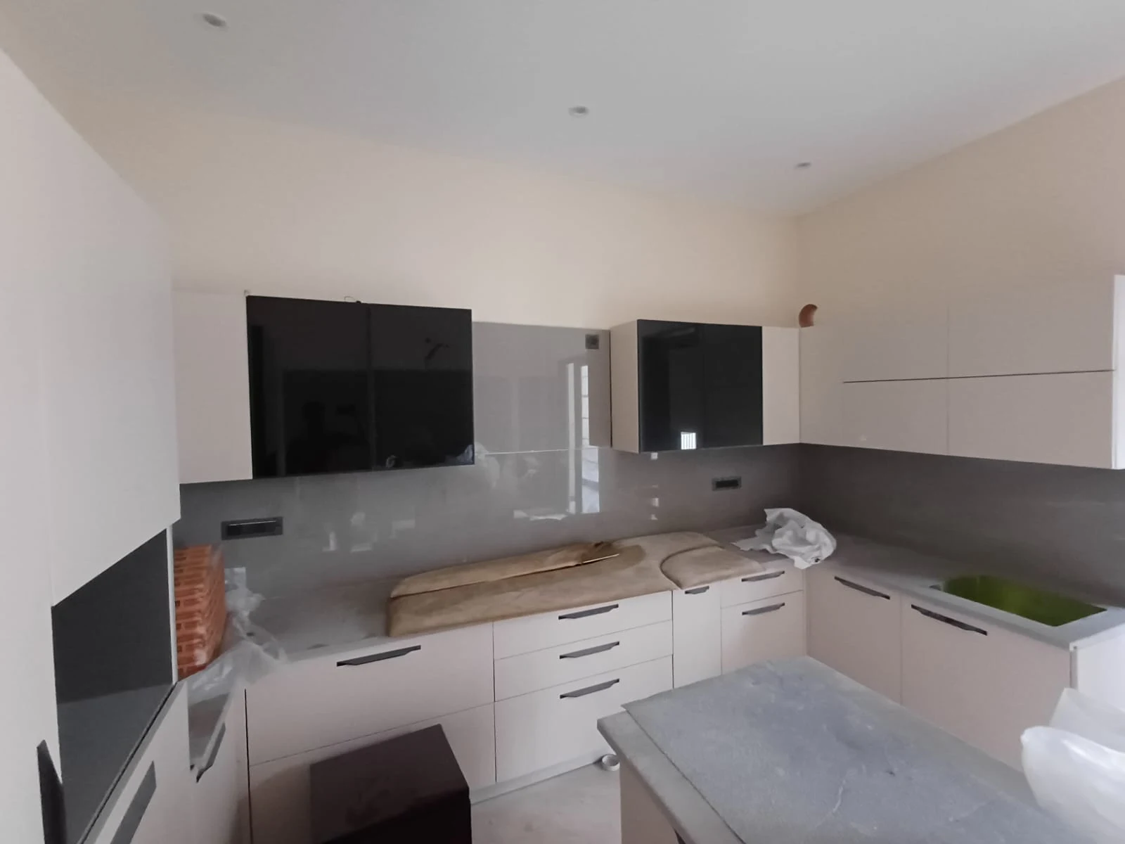 High-gloss champagne beige modular kitchen with black tinted glass wall cabinets Patna